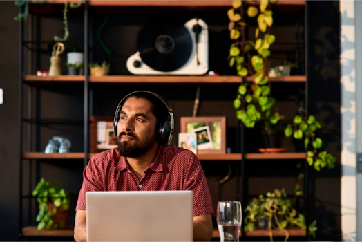 A man wears headphones while listening to a podcast on his computer.